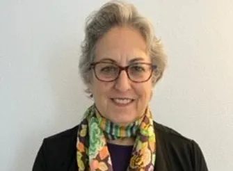 photo of smiling woman with colorful scarf and glasses.